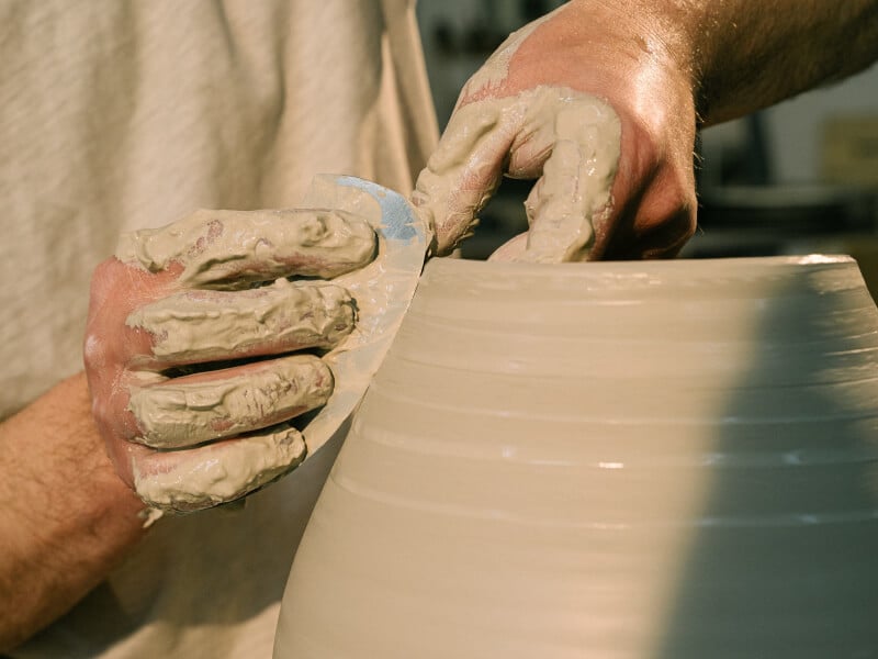 Hands shaping clay on a pottery wheel